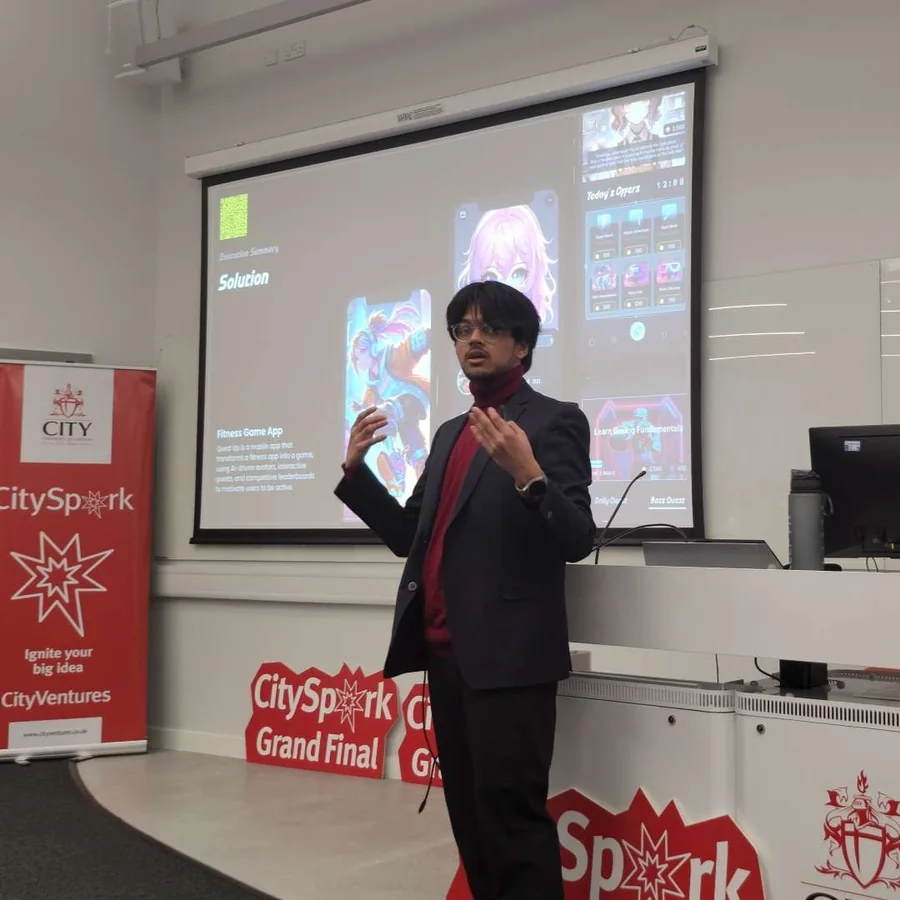 Mahin pitching Quest Up at the CitySpark Grand Final, in front of the slide showing the app’s solution